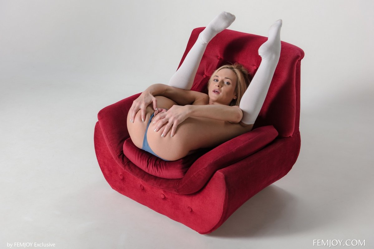 Обнаженная блондиночка широко разводит ноги в красном кресле